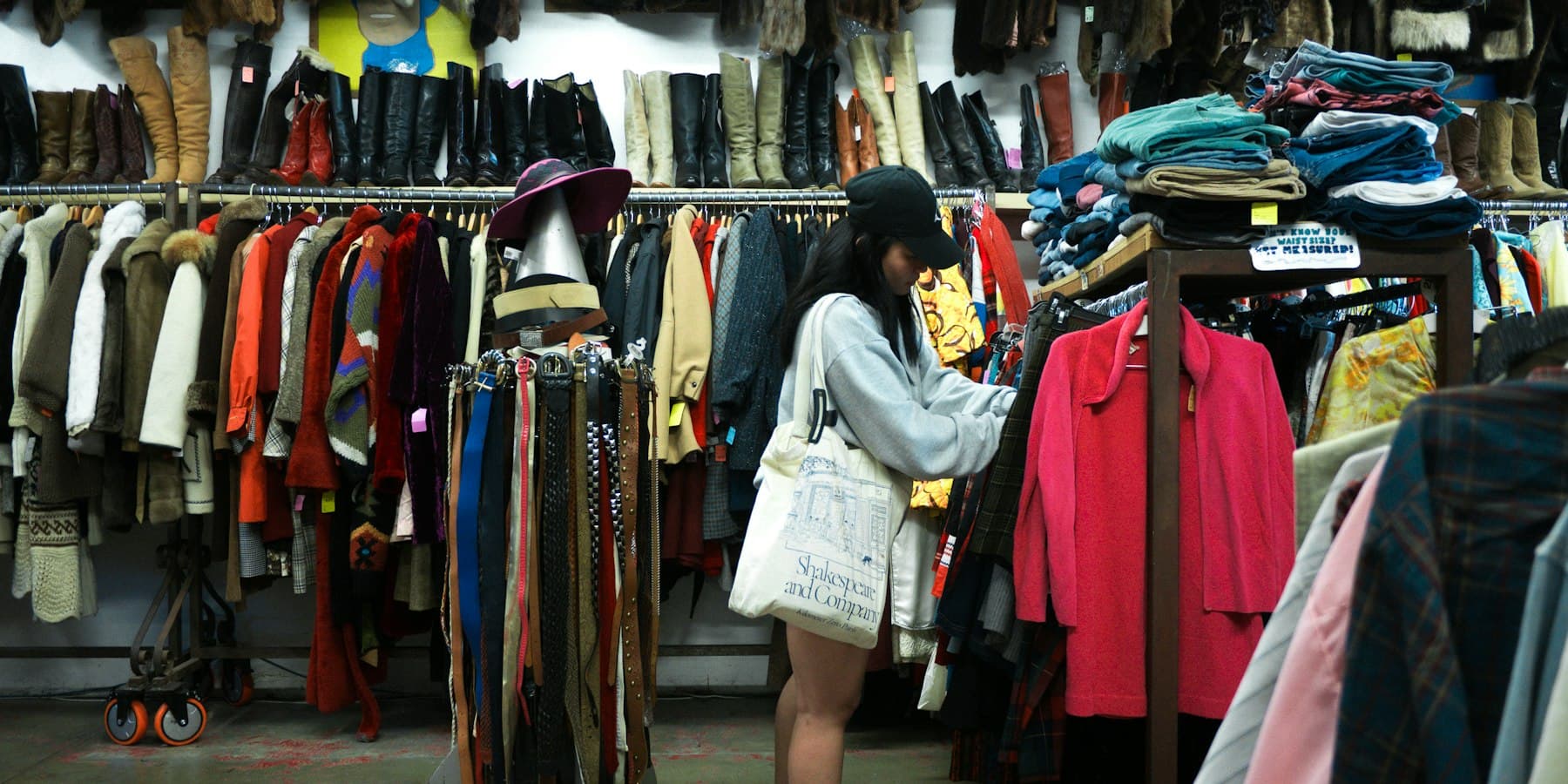 A shopper browsing a rail of second-hand coats in a charity shop