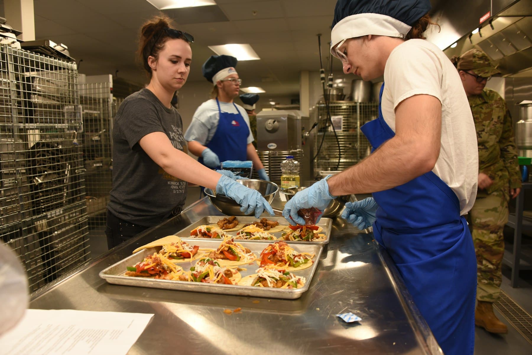 Volunteers in aprons and gloves preparing meals together in a community kitchen