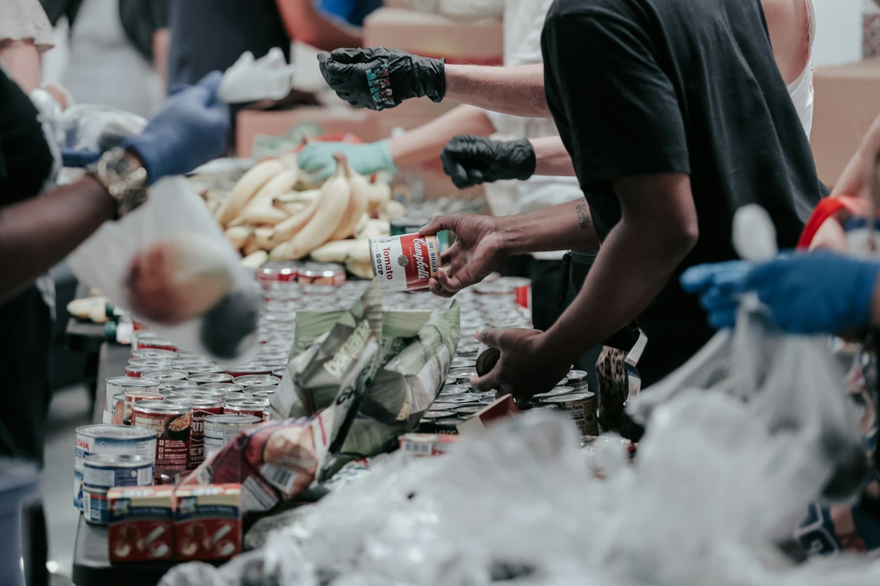 Volunteers handing tins and food across a long table at a food bank