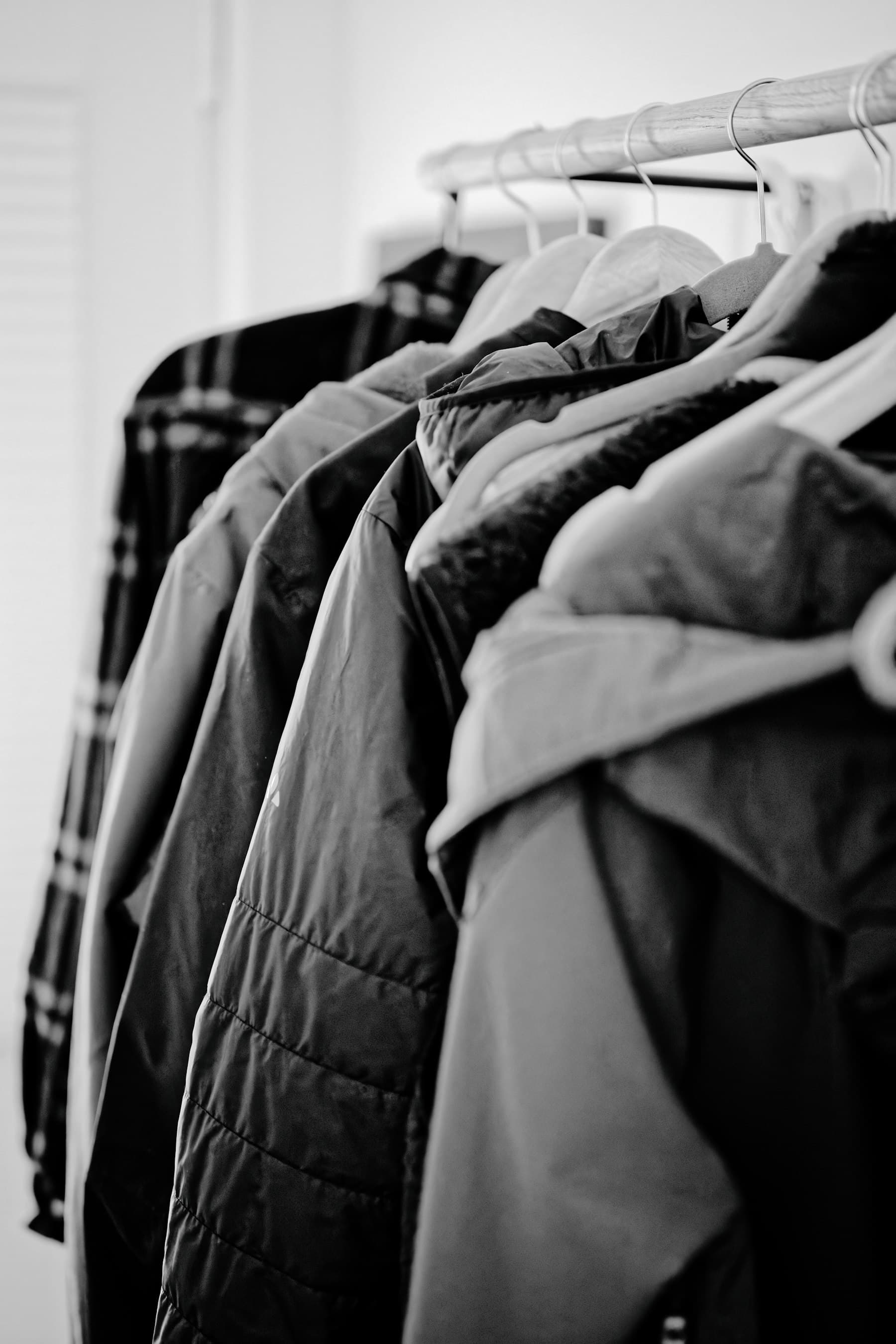 Donated winter coats hanging on a rail, in black and white